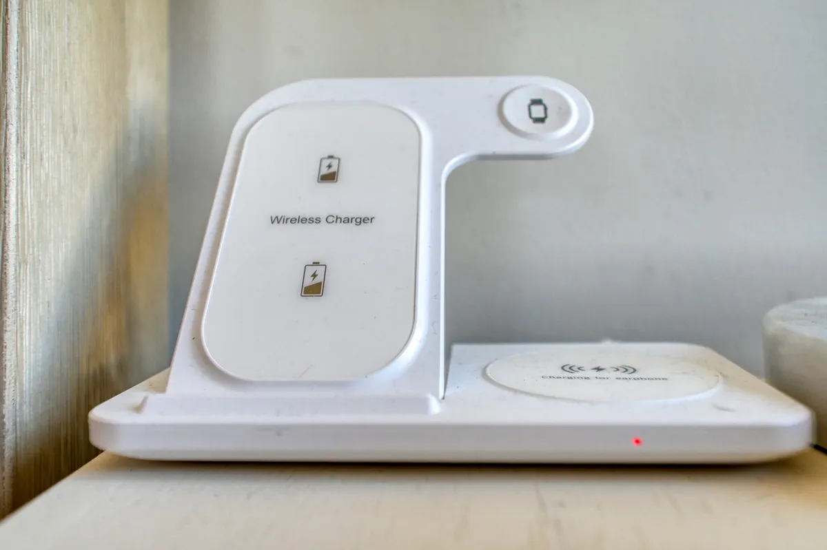 A close-up of a wireless device charging pad in use, highlighting the cottage’s modern conveniences integrated into a classic setting for contemporary comfort.