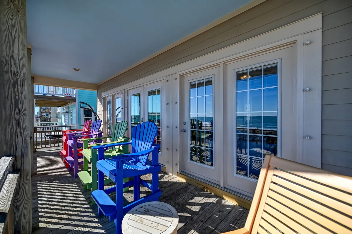 This exterior image features a cheerful arrangement of colorful chairs facing large windows with a sweeping sea view in the background. The space evokes a sense of relaxation and camaraderie, perfect for groups gathering to soak in ocean vistas.