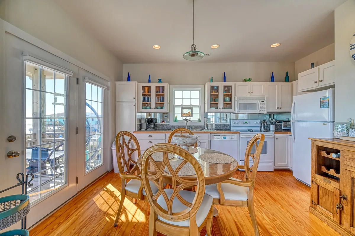 A cheerful kitchen and dining area featuring a wooden dining table, kitchen cabinets, appliances, and windows that bring in natural light. The space is perfect for family meals, cooking together, or enjoying morning coffee while watching the sunrise.